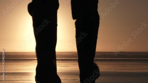 Man at the coast walking out to enjoy the sunset on sandy beach all to himself.