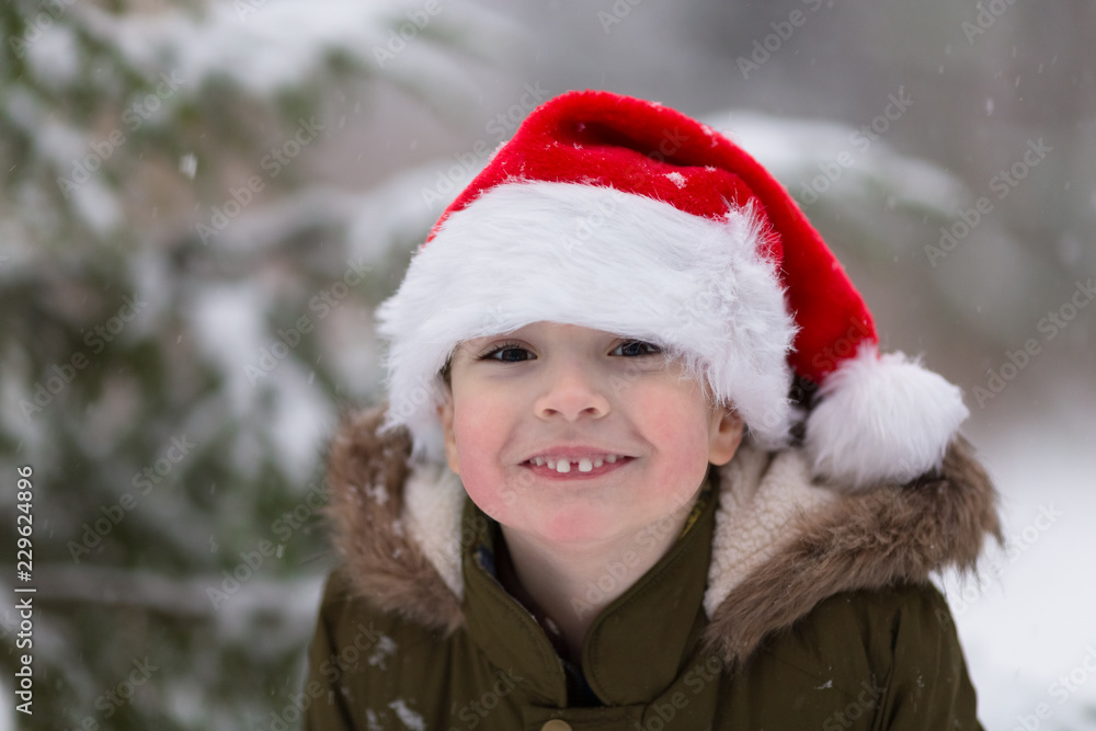 Happy xmas and New Year. Happy smiling boy in Santa red hat. Outdoor winter photo. Christmas and New Year concept. Happy xmas and New Year. Happy smiling boy in Santa red hat. Outdoor winter photo. Christmas and New Year concept.