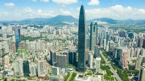 Aerial hyper lapse of Shenzhen cityscape under cloudy sky.
