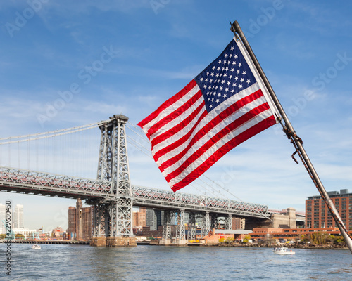 American Flag.  An American flag flies from a boat on the East River in New York City.  In the background is the Williamsburg Bridge connecting Manhattan and Brooklyn.
