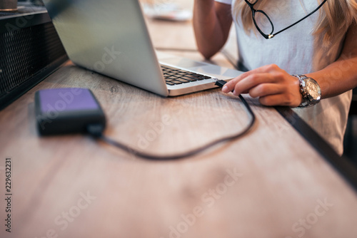 Photos Close-up image of a woman freelancer connecting an external hard drive to the laptop