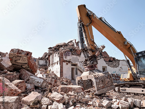 Old house demolition. Excavator working in rubble. Heavy machine