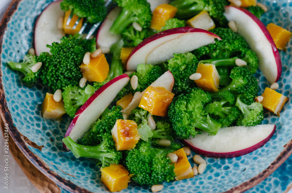 Salad with baked pumpkin, apple, broccoli and pine nuts. Ceramic plates handmade. Rustic style. Salad with baked pumpkin, apple, broccoli and pine nuts. Ceramic plates handmade. Rustic style.