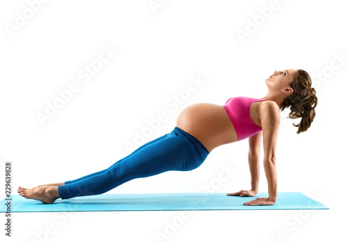 Young beautiful pregnant woman does yoga exercise on last months of pregnancy isolated on white background. Concept of healthy life