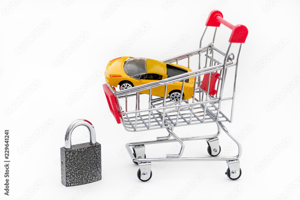 The concept of buying insurance for cars and auto sports. A metal trolley with a yellow toy car and a metal lock next to it on a white background. close up.