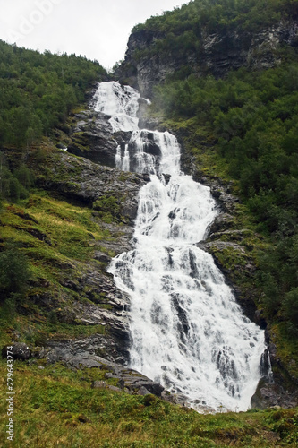 large waterfall in mountainous and wooded areas