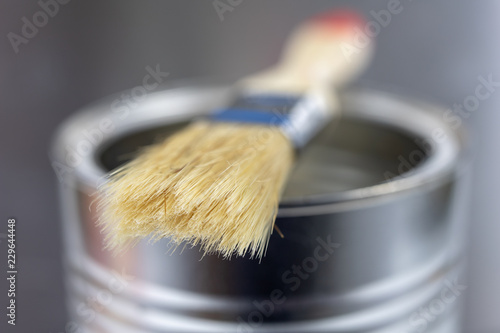 A paint brush and a can of paint on a workshop table. Painting accessories for construction workers.
