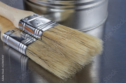 A paint brush and a can of paint on a workshop table. Painting accessories for construction workers.