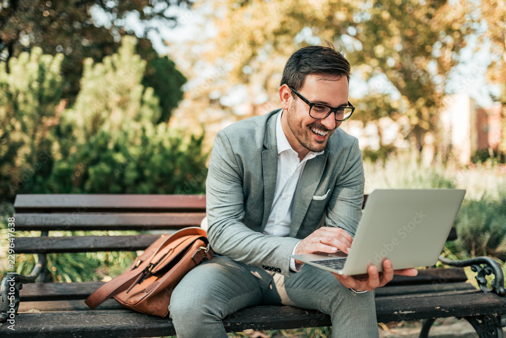 Handsome businessman using laptop in the park. Handsome businessman using laptop in the park.