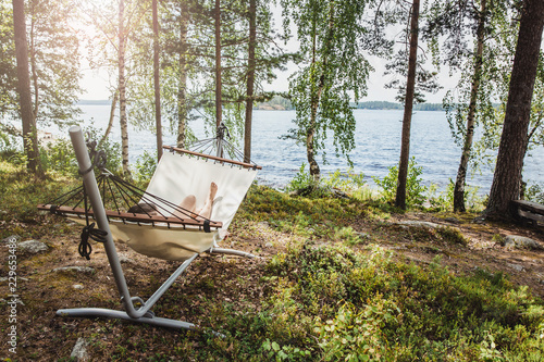 The girl lies in a hammock on the lake in the forest at sun, vacation concept.