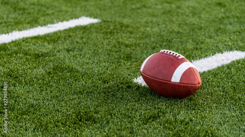 A brown leather american football on a green playing field