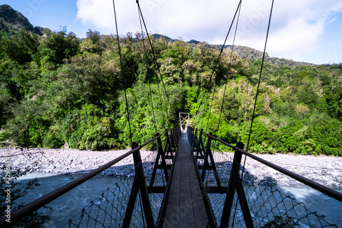 The wooden swing bridge in the green nature. photo