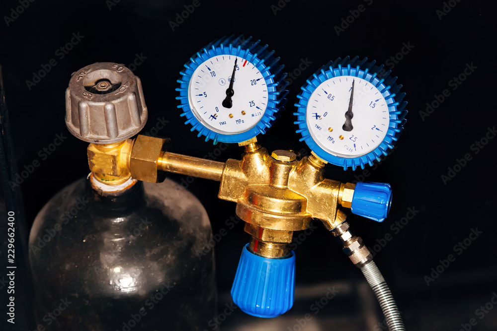 Gas cylinder with reducer, pressure gauge and valve on black background Gas cylinder with reducer, pressure gauge and valve on black background