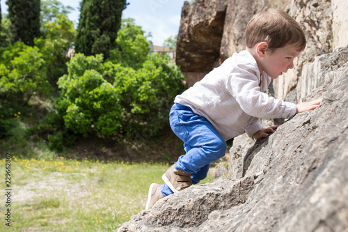 3 years old child boy climbing rock photo