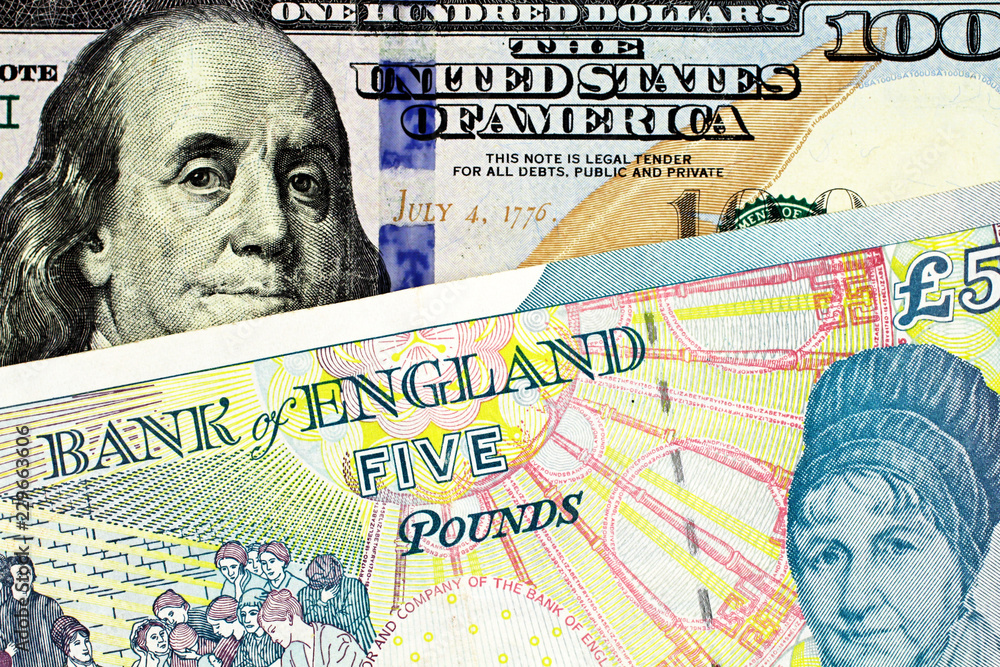 A close up image of a five pound note from England with a blue, American one hundred note