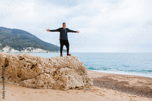 Italy, Vieste, relaxed man with arms outstretched standing on a rock on Vignanotica Beach photo