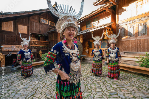 Smiling women in headdresses and traditional clothing standing in village square photo