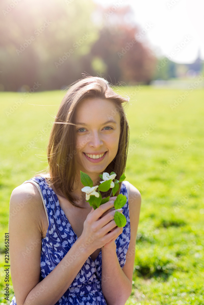 Portrait of smiling young woman in a park holding flowers Portrait of smiling young woman in a park holding flowers