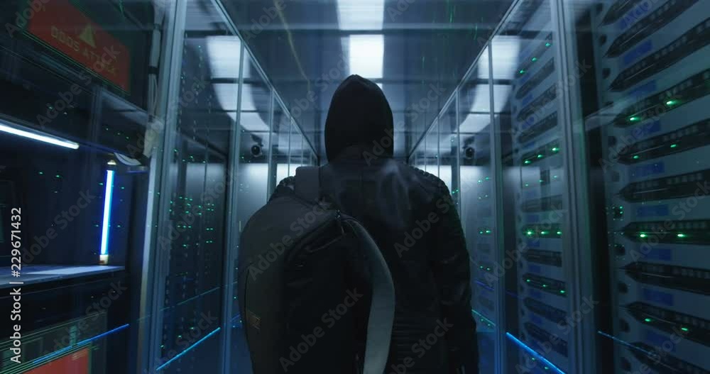 Medium, slow motion shot from behind of a hacker with a backpack walking through corporate data center with rows of working rack servers Medium, slow motion shot from behind of a hacker with a backpack walking through corporate data center with rows of working rack servers