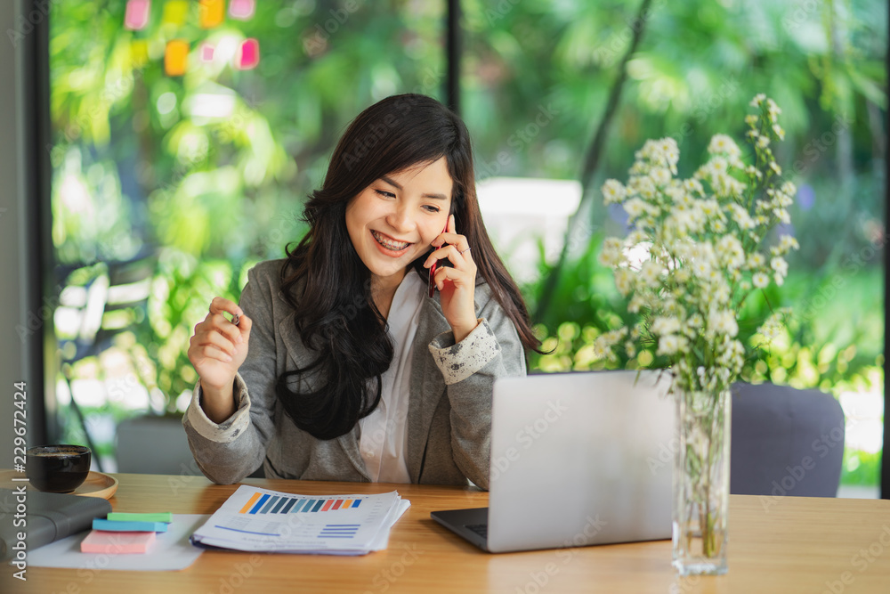 Portrait of an attractive young woman holding her phone while working in coffee shop. Portrait of an attractive young woman holding her phone while working in coffee shop.