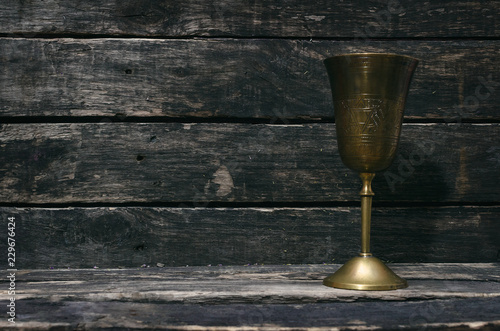 Canvas Print Brass goblet on wooden table background with copy space.