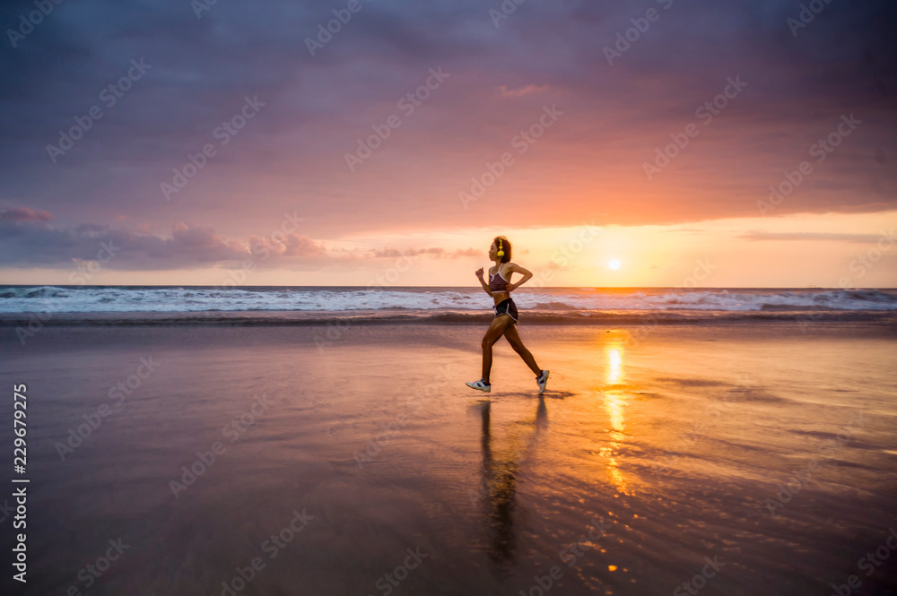 silhouette of fit and athletic Asian Chinese sporty woman running on beautiful beach doing jogging workout on sunset in fitness healthy lifestyle and summer outdoors activity