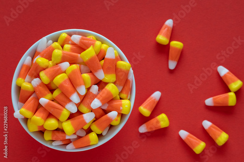 Canvastavla White dish filled with Halloween candy corn on an orange background, with some c