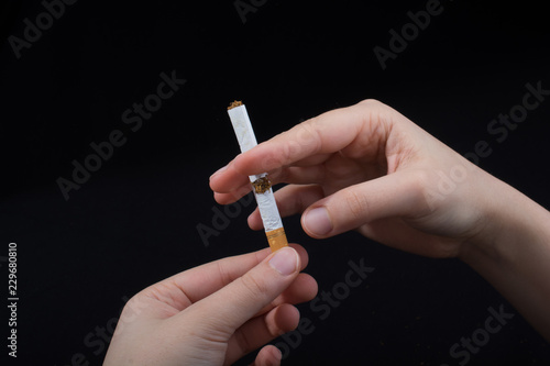 Hand is breaking a cigarette on black background