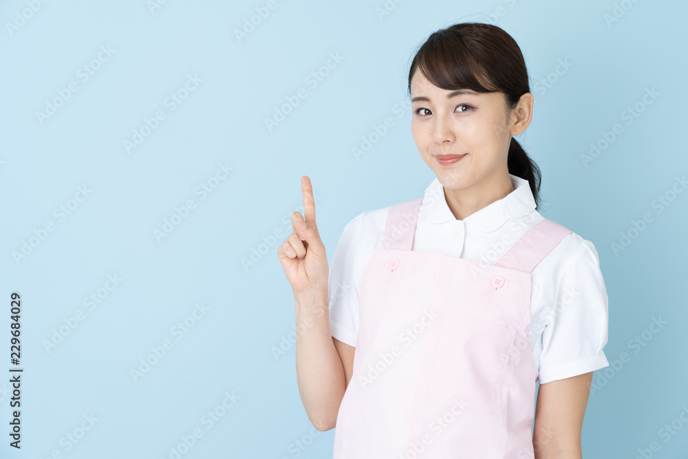 portrait of young asian nurse wearing apron on blue background portrait of young asian nurse wearing apron on blue background