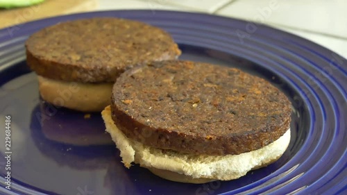 A vegan chef cooking and assembling two healthy tomato and avocado vegetarian burgers for lunch. photo