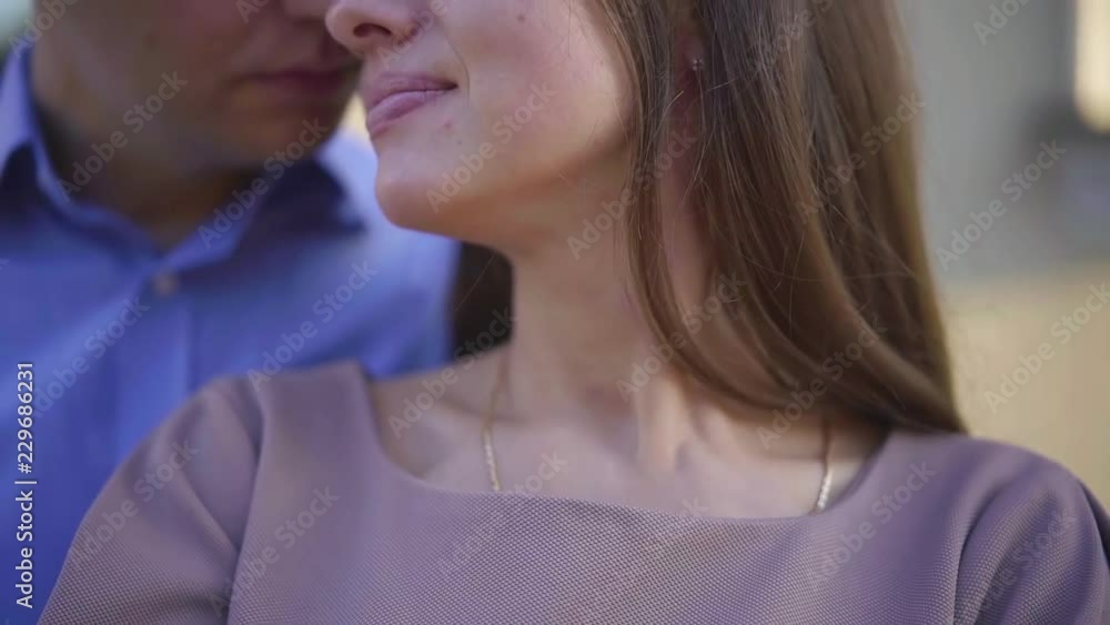 pretty adult woman is enjoying embrace of her beloved husband, man is kissing wife in cheek and forehead pretty adult woman is enjoying embrace of her beloved husband, man is kissing wife in cheek and forehead