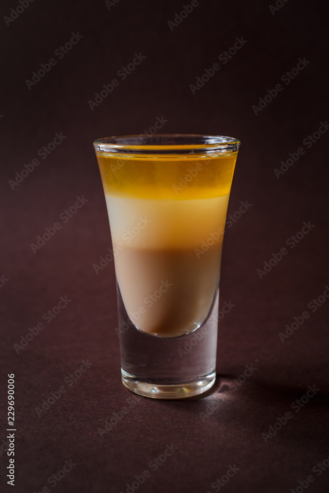 BMW alcoholic shot glass with irish cream, whiskey, coconut liquor on elegant dark brown background BMW alcoholic shot glass with irish cream, whiskey, coconut liquor on elegant dark brown background