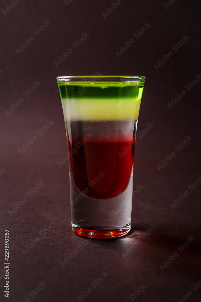 Alcoholic shot glass with grenadine, absent on elegant dark brown background Alcoholic shot glass with grenadine, absent on elegant dark brown background