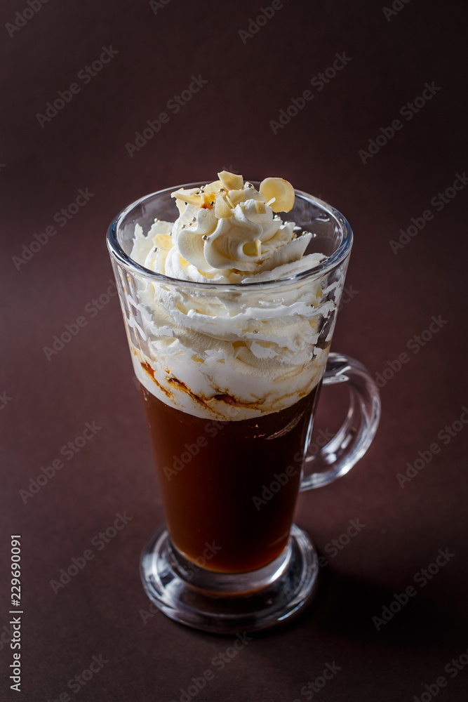 Glass of frappucino with whipped cream and almonds shaving on elegant dark brown background Glass of frappucino with whipped cream and almonds shaving on elegant dark brown background