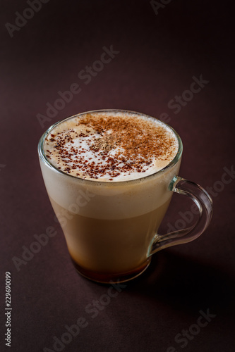 Fototapeta Naklejka Na Ścianę i Meble -  Glass of coffee with chocolate topping on elegant dark brown background