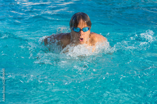 Close up action shot of teenage boy, young athlete swimming butterfly stroke. Sport, recreation, lifestyle concept.