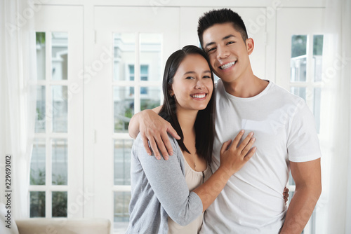 Happy young mixed-race couple standing in their new house