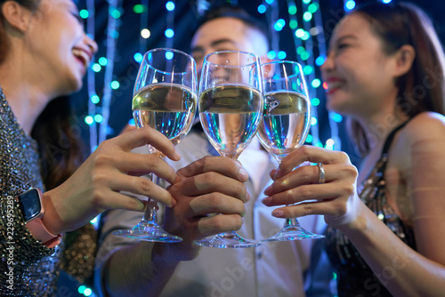 Young people clinking glasses of champagne at night party