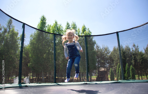 Little child enjoys jumping on trampoline at the park. photo