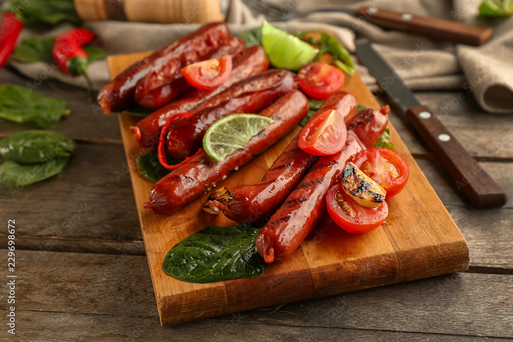 Wooden board with delicious grilled sausages and vegetables on table Wooden board with delicious grilled sausages and vegetables on table