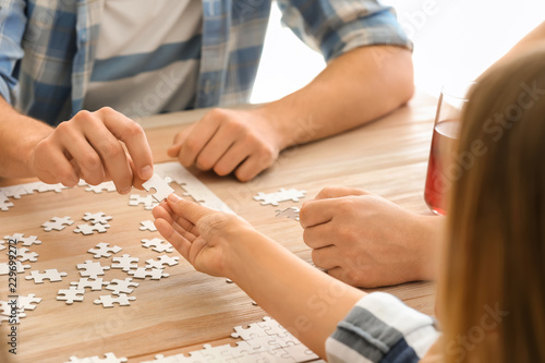 Group of people assembling puzzle on wooden table