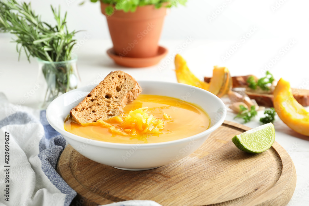 Plate with tasty pumpkin cream soup on wooden board Plate with tasty pumpkin cream soup on wooden board