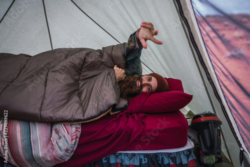 Cheerful traveler lying on bed in tent