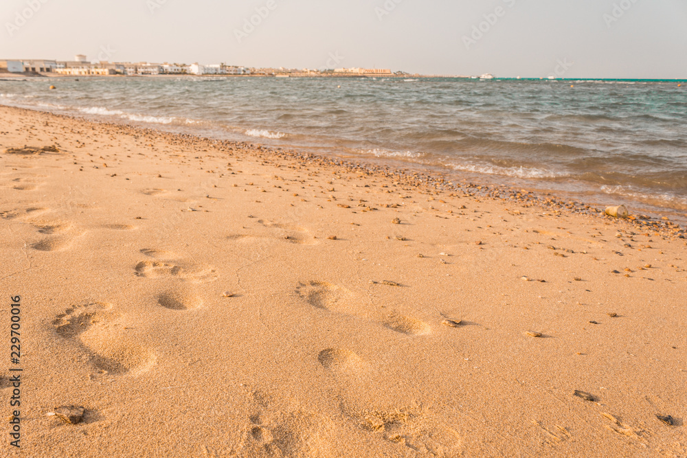 Footprints in the sand. Beautiful sandy tropical beach with sea waves. Footprints in the sand. Beautiful sandy tropical beach with sea waves.
