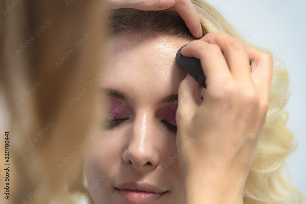 The work of a professional make-up artist, beautician, makes makeup on the face of a blonde girl with shadows on the eyes. The work of a professional make-up artist, beautician, makes makeup on the face of a blonde girl with shadows on the eyes.