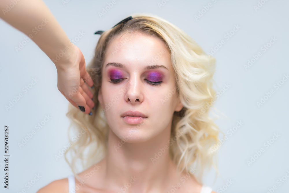 The work of a professional make-up artist, beautician, makes makeup on the face of a blonde girl with shadows on the eyes. The work of a professional make-up artist, beautician, makes makeup on the face of a blonde girl with shadows on the eyes.