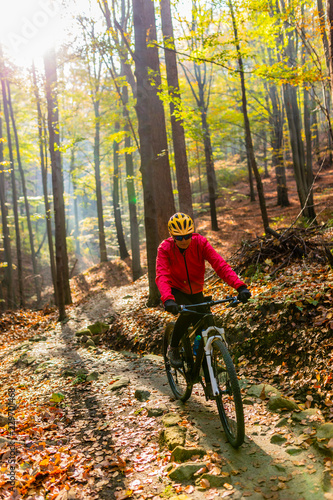 Cycling, mountain bikeing woman on cycle trail in autumn forest. Mountain biking in autumn landscape forest. Woman cycling MTB flow uphill trail.