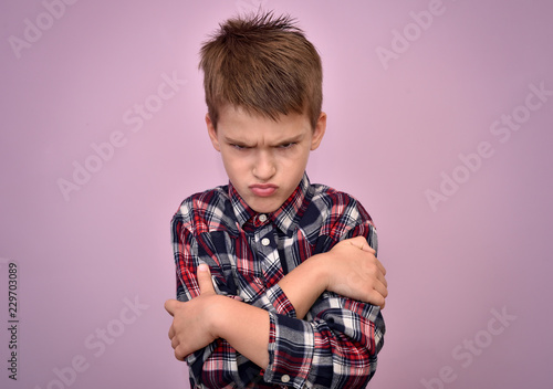 Angry and pouting cute young boy with crossed arms