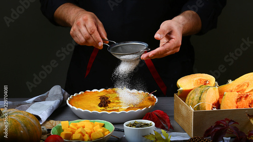 фотографія Close the chef's hands with sugar powder splashes cooking pumpkin pie