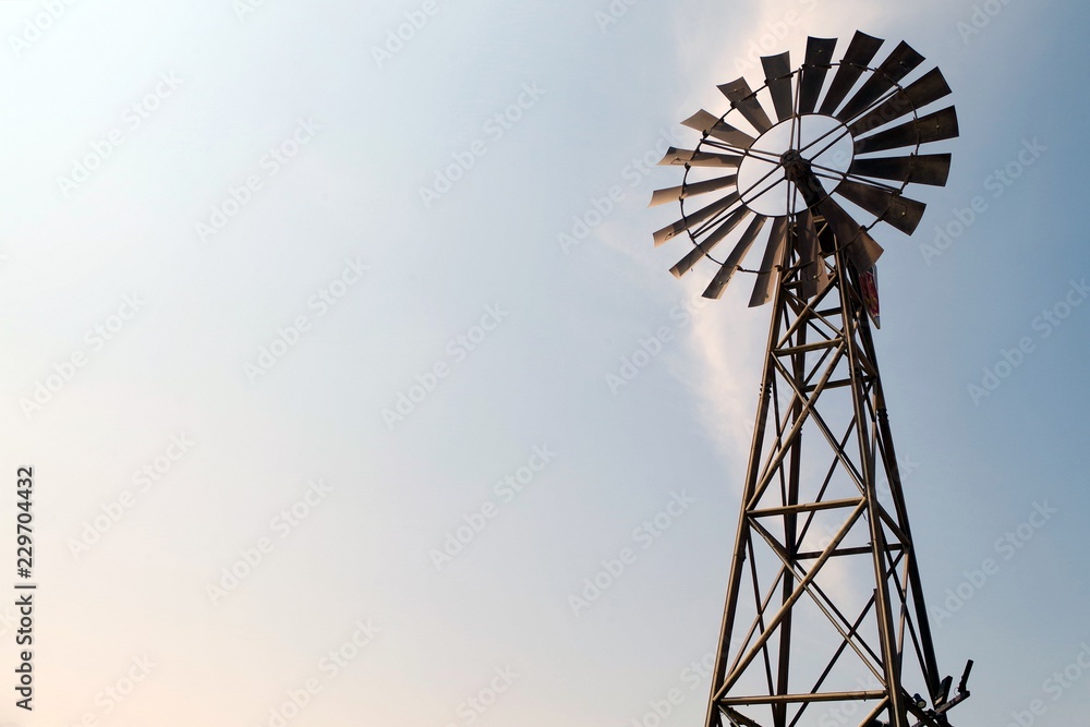 A Windmill silhouette with bright and blue sky. Beautiful american countryside icon. A Windmill silhouette with bright and blue sky. Beautiful american countryside icon.
